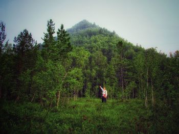 Man walking by trees in forest against sky