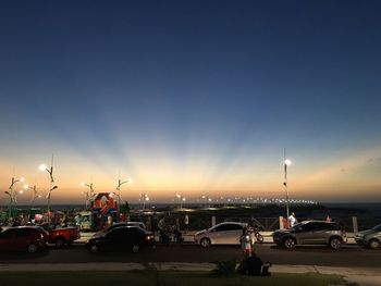 Cars on illuminated road against sky during sunset