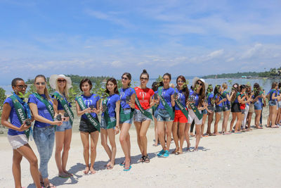 Group of people at beach against sky