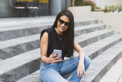 Hispanic woman typing on the phone on the street