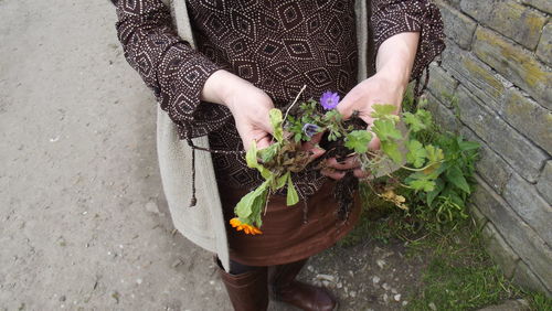 Low section of woman holding flowers