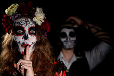 Portrait of woman wearing mask against black background