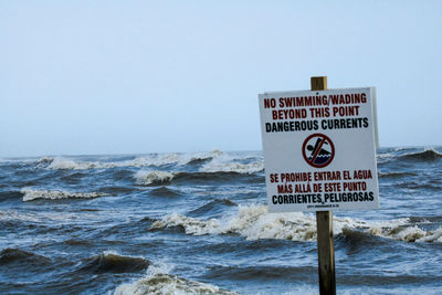 Information sign on beach against sky