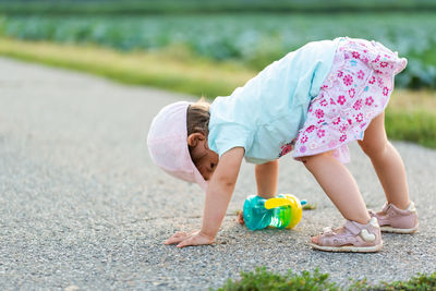 Baby sitting on a asphalt road between rural agricultural fields. children outdoors concept