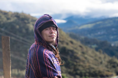 Portrait of young woman standing against mountain