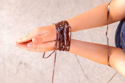 Cropped hands of person tied with reel over land