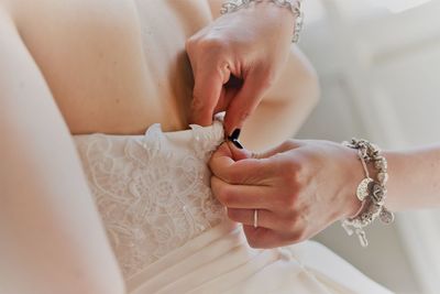 Close-up of friend helping bride to get dressed up