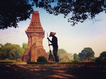 Man standing by temple against sky