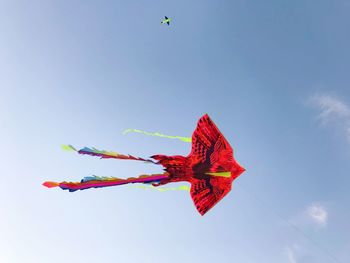 Low angle view of kites flying against clear blue sky