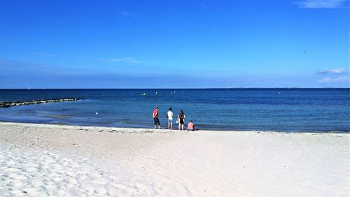 People on beach against blue sky