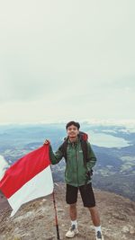 Rear view of man holding indonesian flag against sky