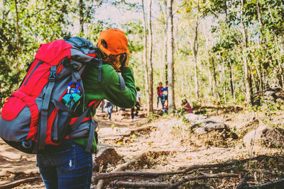 Rear view of man taking photograph while standing in forest