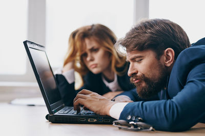 Tired businessman working on laptop at office