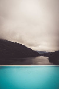 Swimming pool by sea against sky