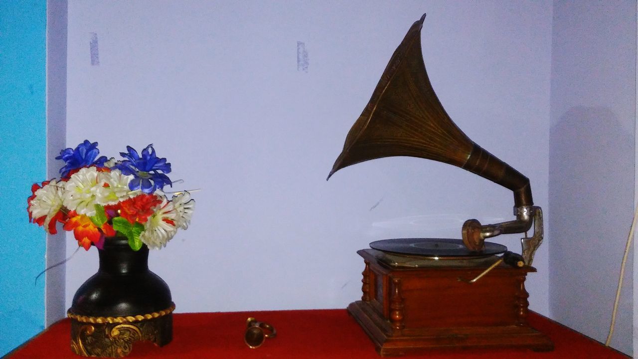 CLOSE-UP OF FLOWER VASE ON TABLE AGAINST WALL