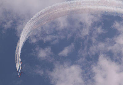 Low angle view of vapor trails and planes against sky