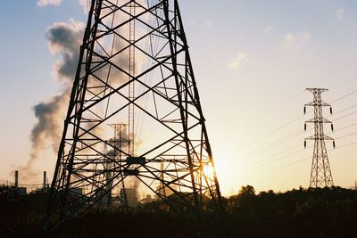 Low angle view of silhouette electricity pylon against sky