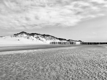 Scenic view of beach against cloudy sky