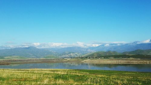 Scenic view of lake and mountains against clear blue sky