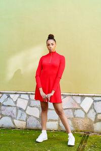 Portrait of young woman standing against wall