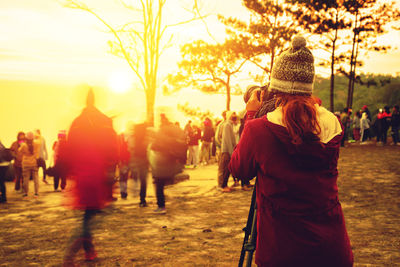 Rear view of people walking in city during sunset