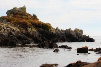 Rock formation on sea shore against sky