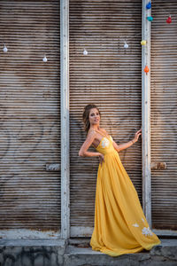 Portrait of woman standing against yellow door