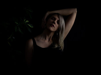 Portrait of young woman against black background