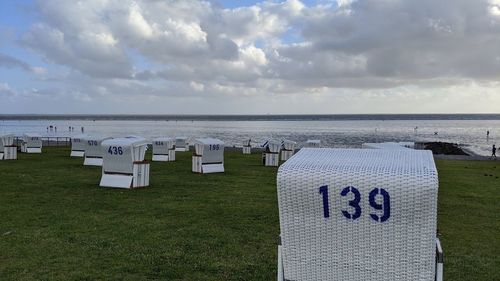 Hooded chairs on beach against sky