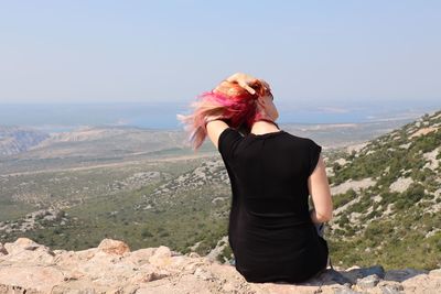 Midsection of woman standing on mountain against sky