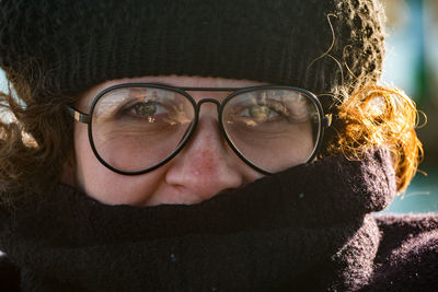 Close of woman with cap and glasses looking at camera.