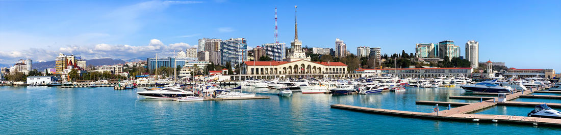 Sailboats moored in harbor against buildings in city