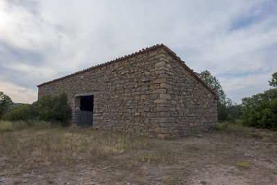 Old house on field against sky