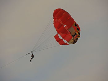 Low angle view of people flying kite against sky