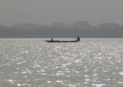 Distant view of men sailing boat on sea