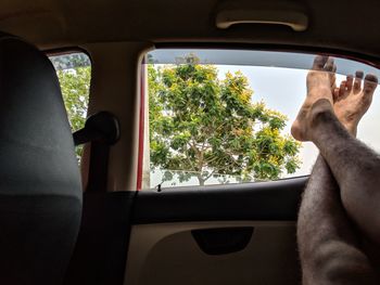 Low section of man resting legs on car window