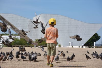 Rear view of women holding umbrella against clear sky