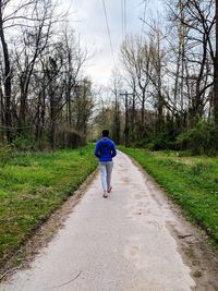 Full length rear view of man walking on footpath