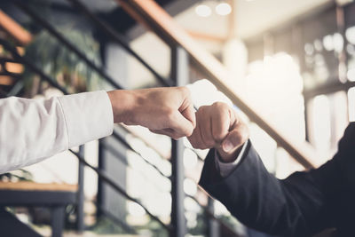 Cropped image of businessmen fist bumping in office