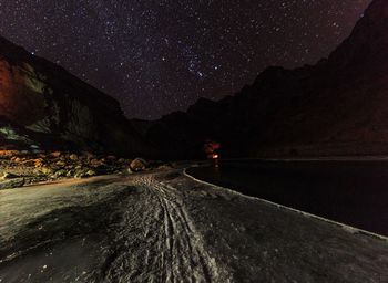 Road amidst mountains against sky at night