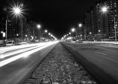 Light trails on city street against clear sky at night