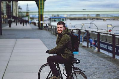 Portrait of man riding bicycle on bridge in city
