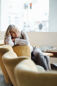 Woman leaning on chair while sitting in coffee shop