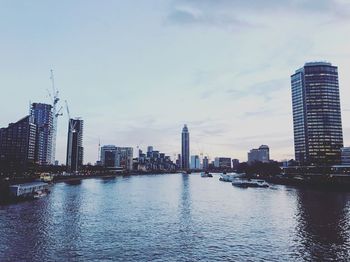 City at waterfront against cloudy sky