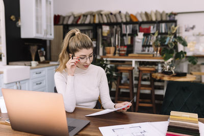 Woman using mobile phone while sitting on table