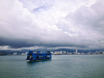 Boats in sea against cloudy sky