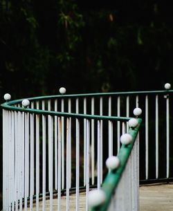 Close-up of white fence by railing in park