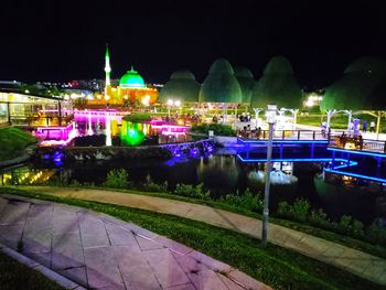 Illuminated building by river at night