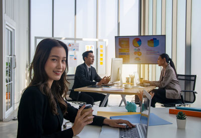 Portrait of young woman using mobile phone while sitting on table