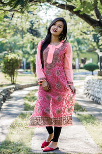 Full length of woman standing against pink wall